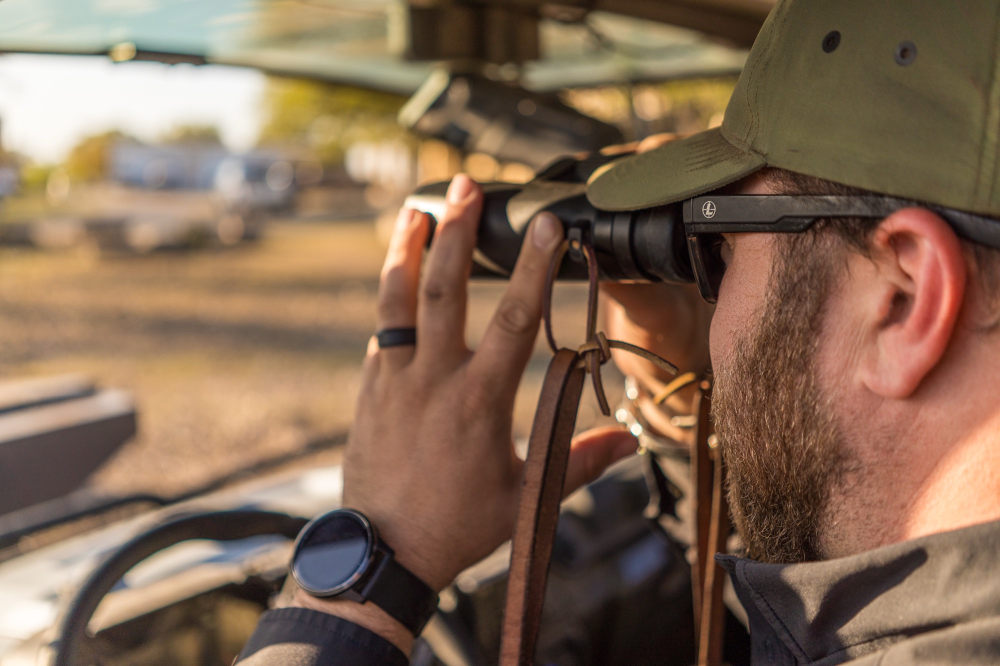 A close view of a guide looking through binoculars, hand steadying the barrels
