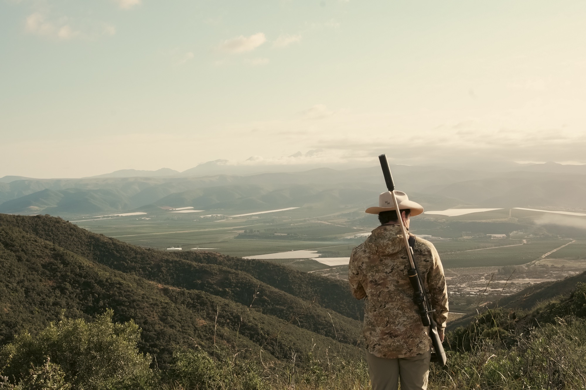 A figure on a high ridge looking out across a broad farmed valley